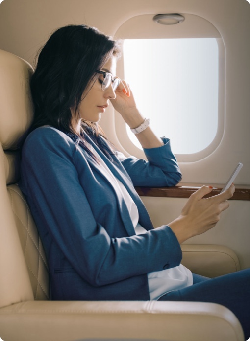 Frau im Flugzeugsitz schaut auf ein Smartphone