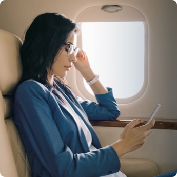 Frau im Flugzeugsitz schaut auf ein Smartphone